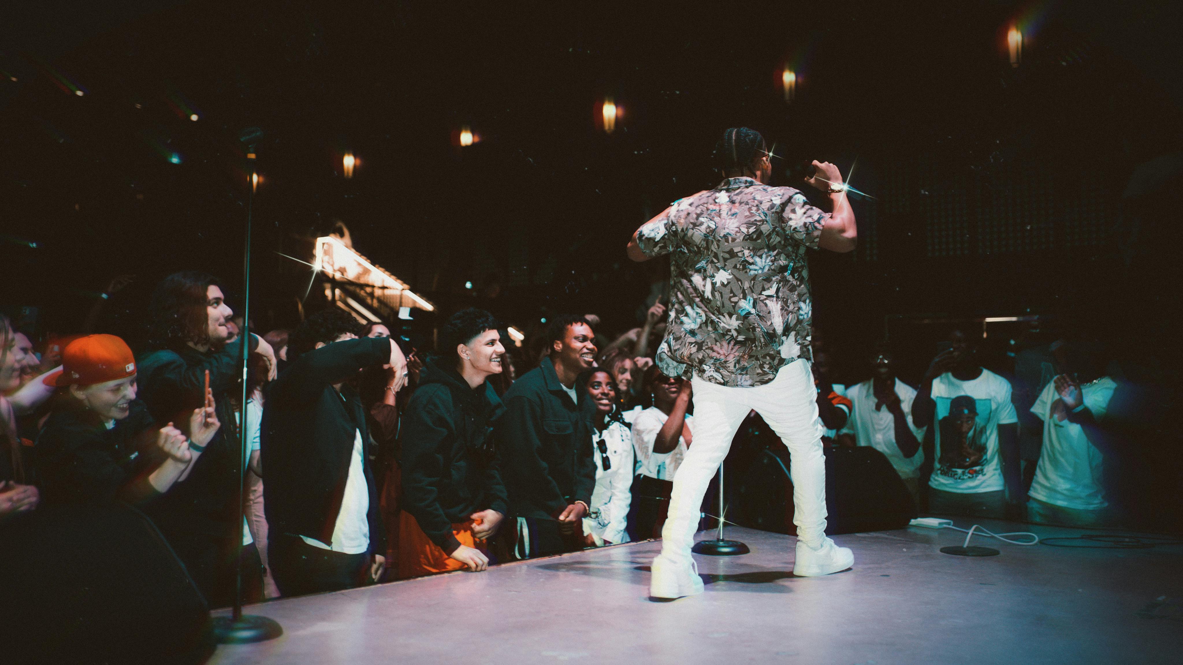 A hip-hop artist on stage, performing in front of a crowd.