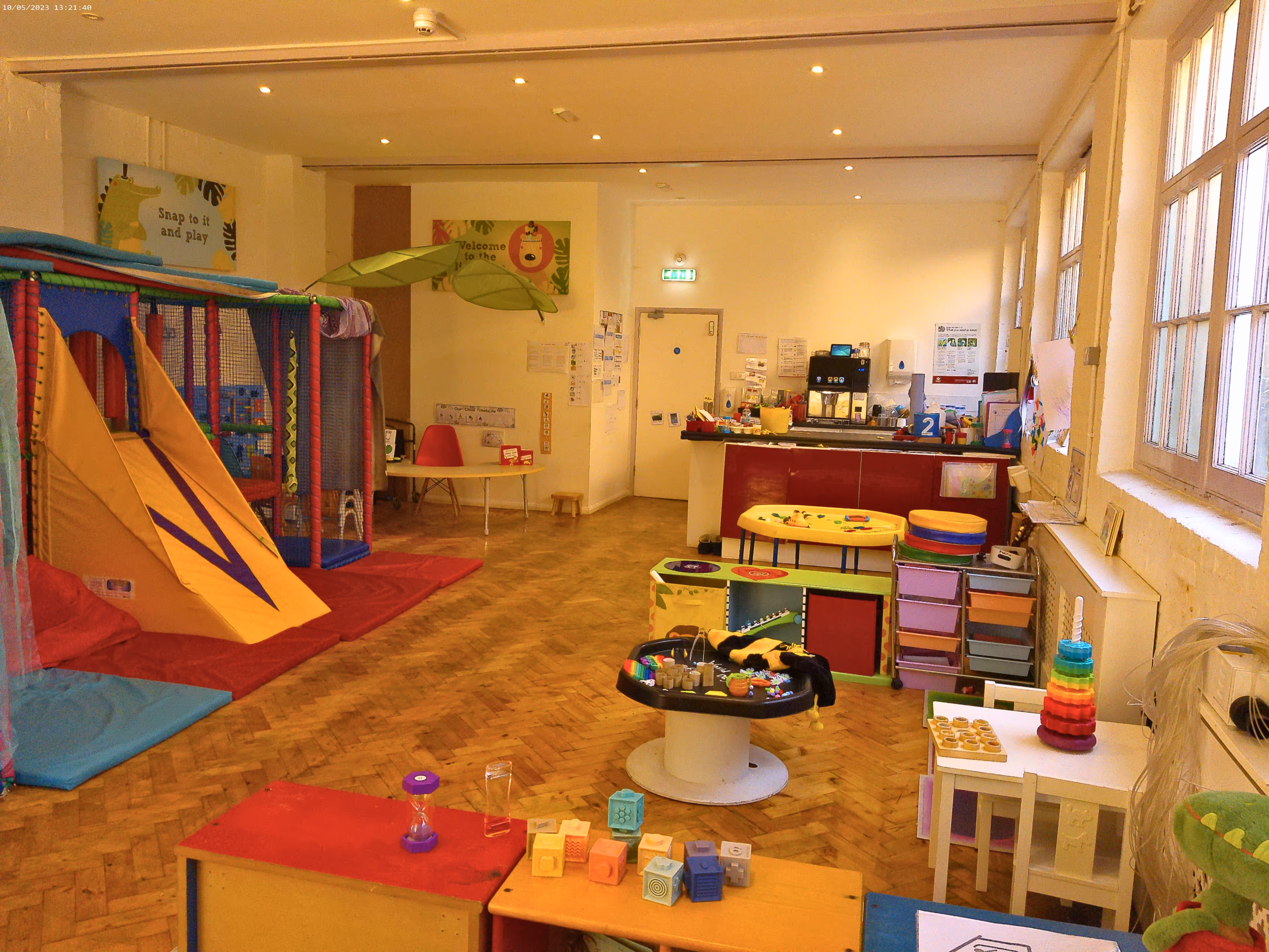 A colorful children's playroom with a slide, toys, and tables arranged around the room.