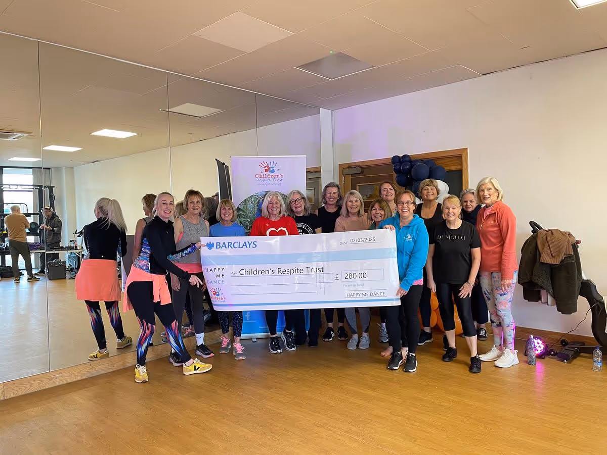 A group of women hold a large check for £280.00, benefiting the Children's Respite Trust.