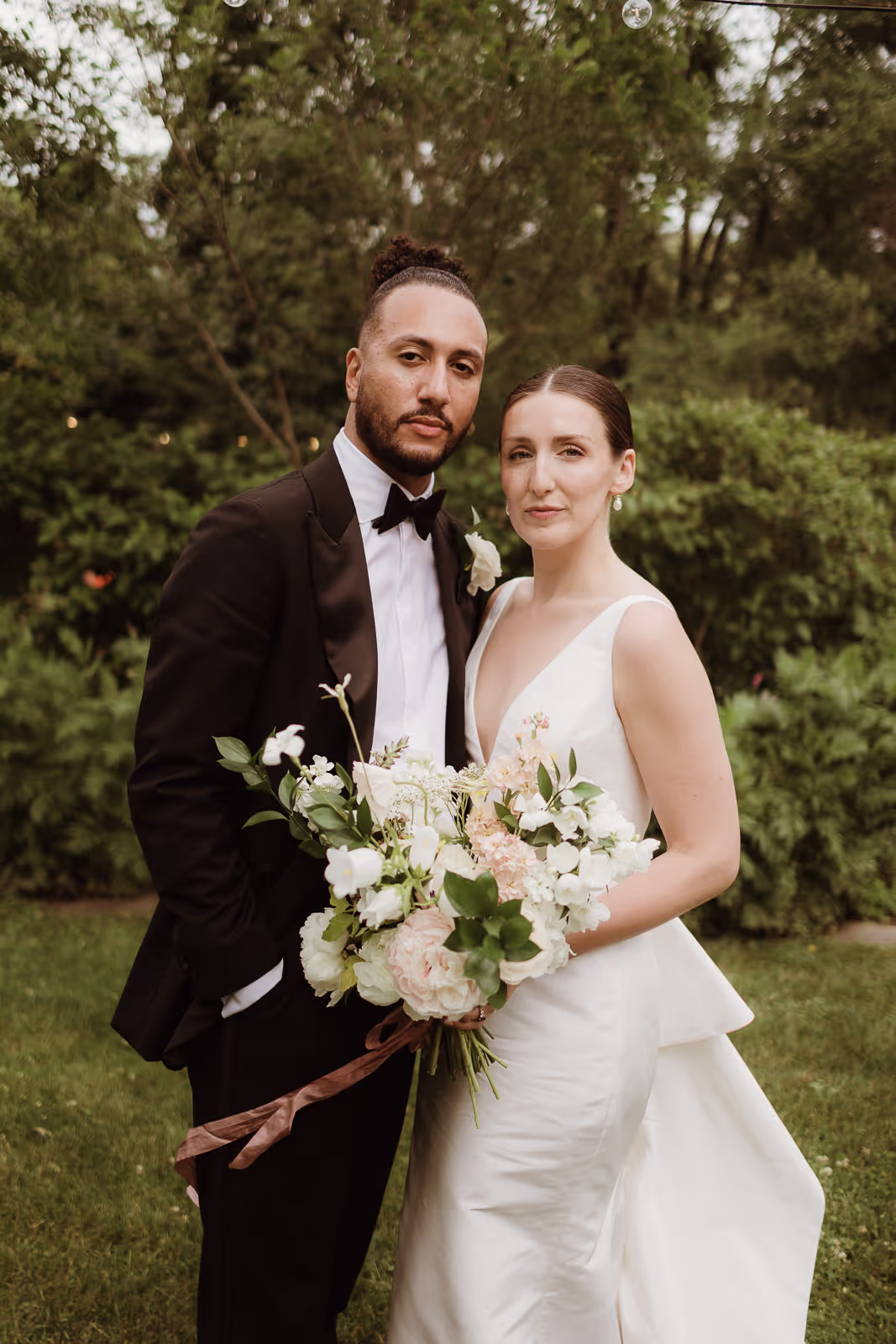 Bride and groom portrait with a white and blush bouquet in a summer garden