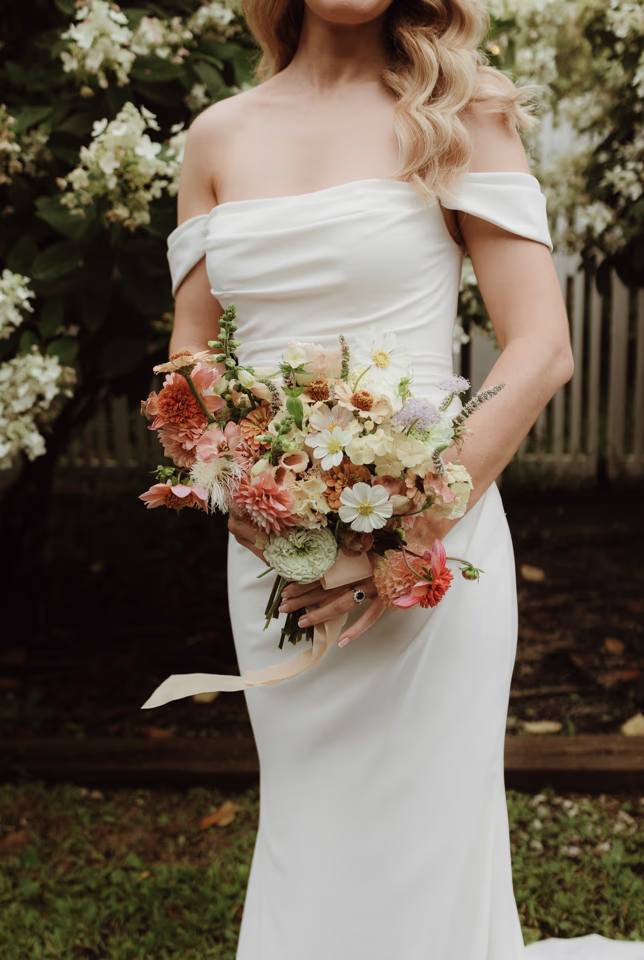 Bride in an off-the-shoulder gown holding a peach and white bouquet at a Hudson Valley wedding