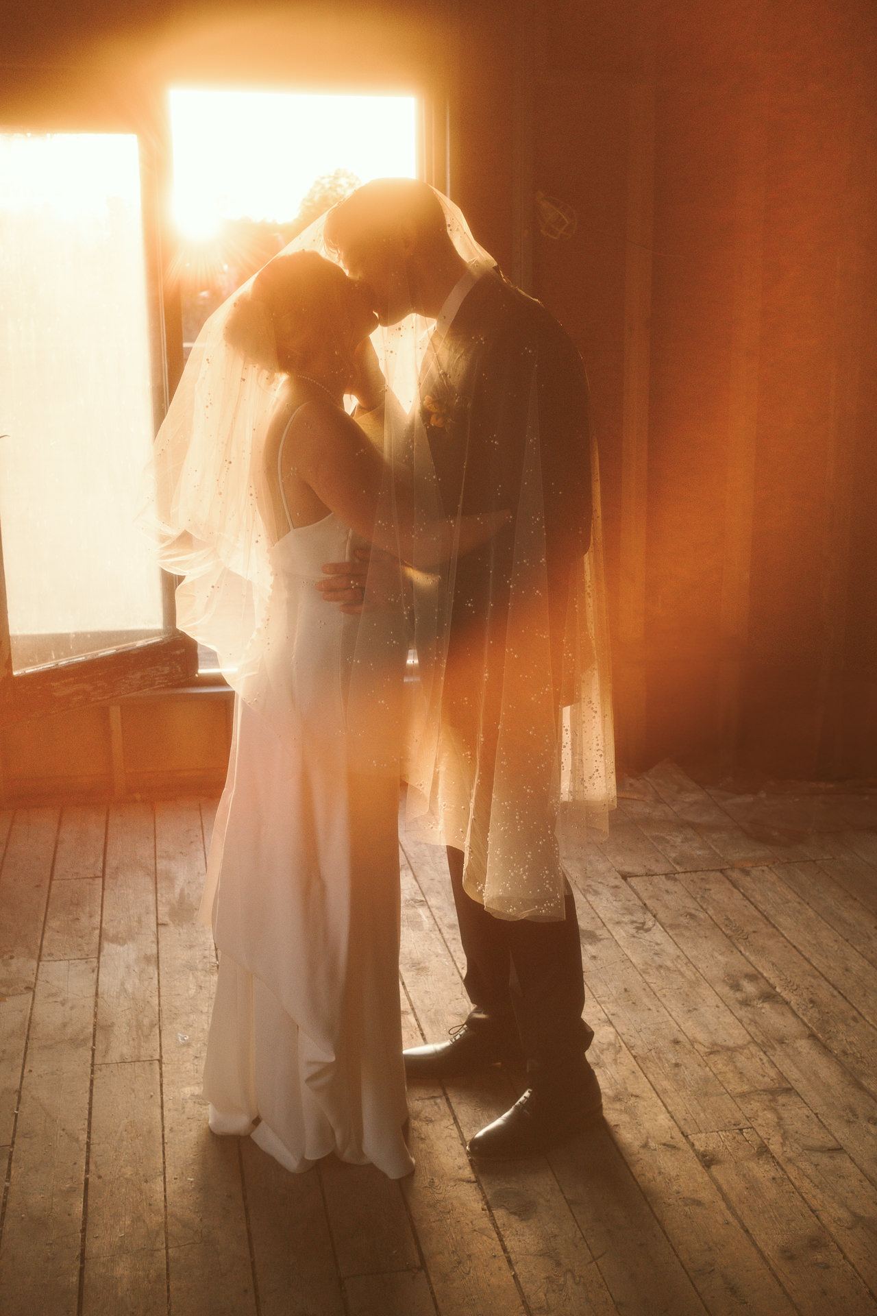 Couple embracing in warm window light at a Revolution Hall wedding in Troy, New York