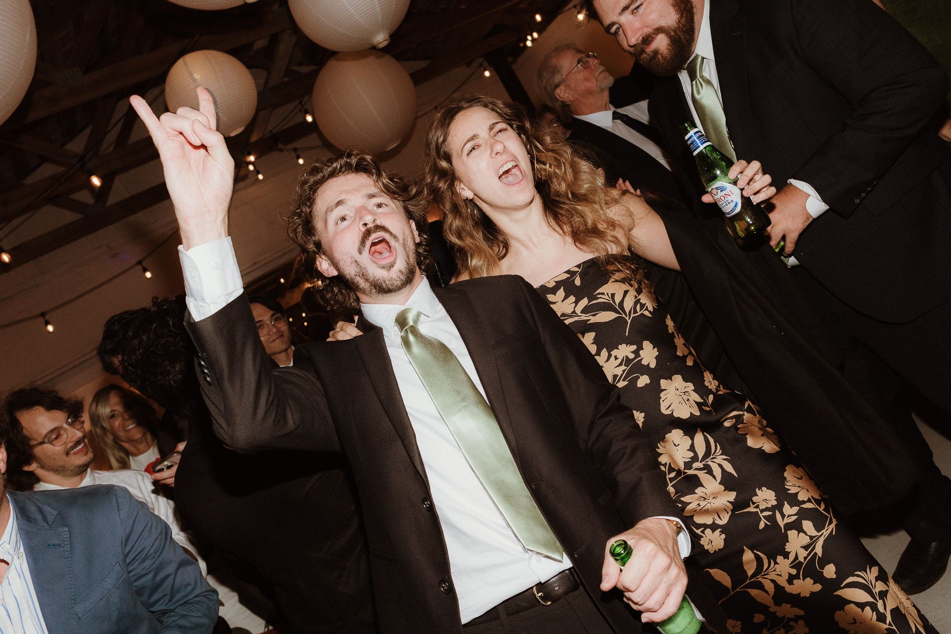 Guests dancing beneath paper lanterns and string lights at a summer farm wedding reception