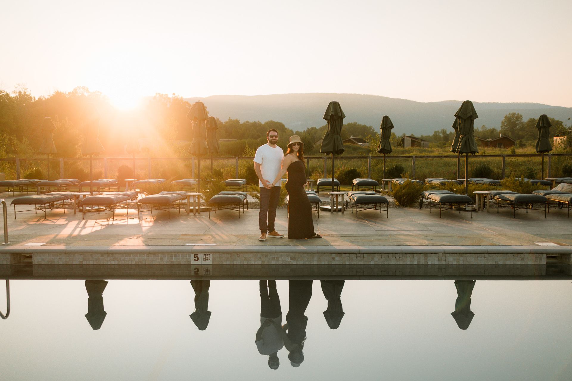 Couple standing at the edge of a reflecting pool at sunset at a Wildflower Farms wedding