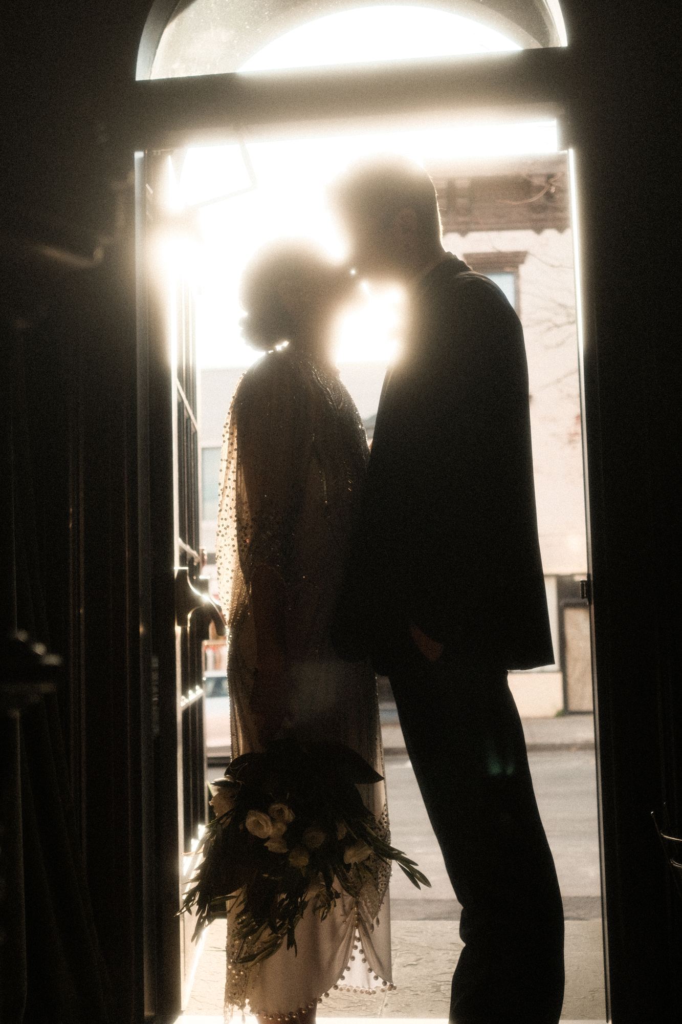 Silhouette of a couple framed in a sunlit doorway before the ceremony