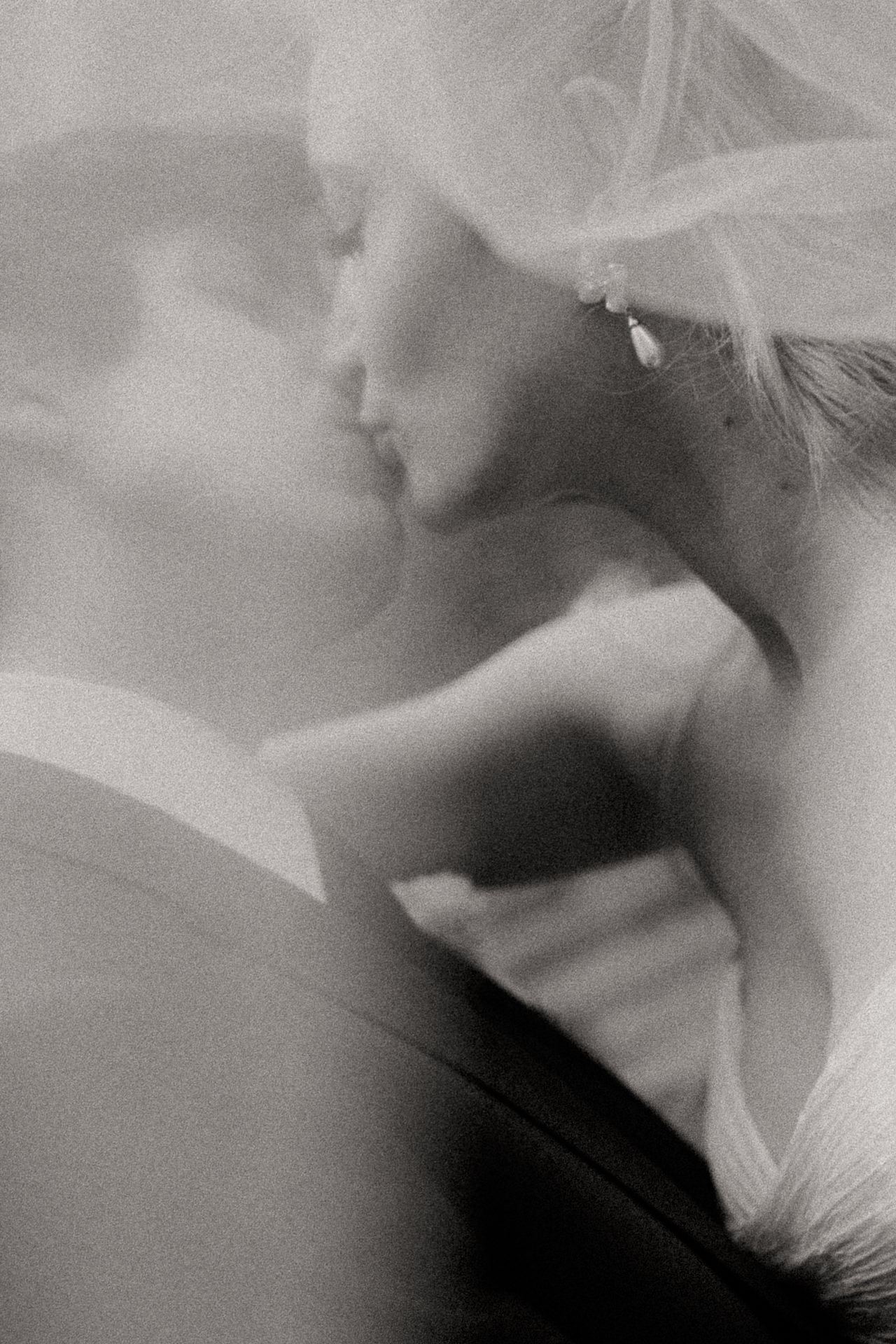 Black and white portrait of a bride and groom kissing through her veil at a Forest Lake Camp wedding