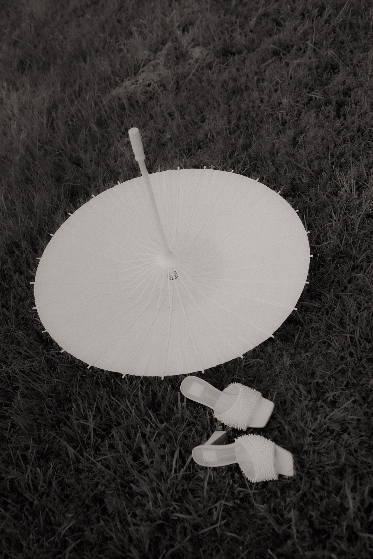 White parasol and satin shoes laid out on the lawn before an Old Mill Guesthouse wedding