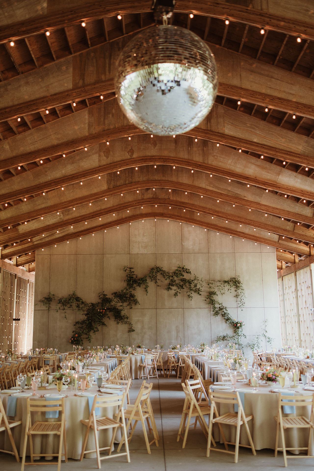 Barn reception with a disco ball and string lights at a Gather Greene summer wedding