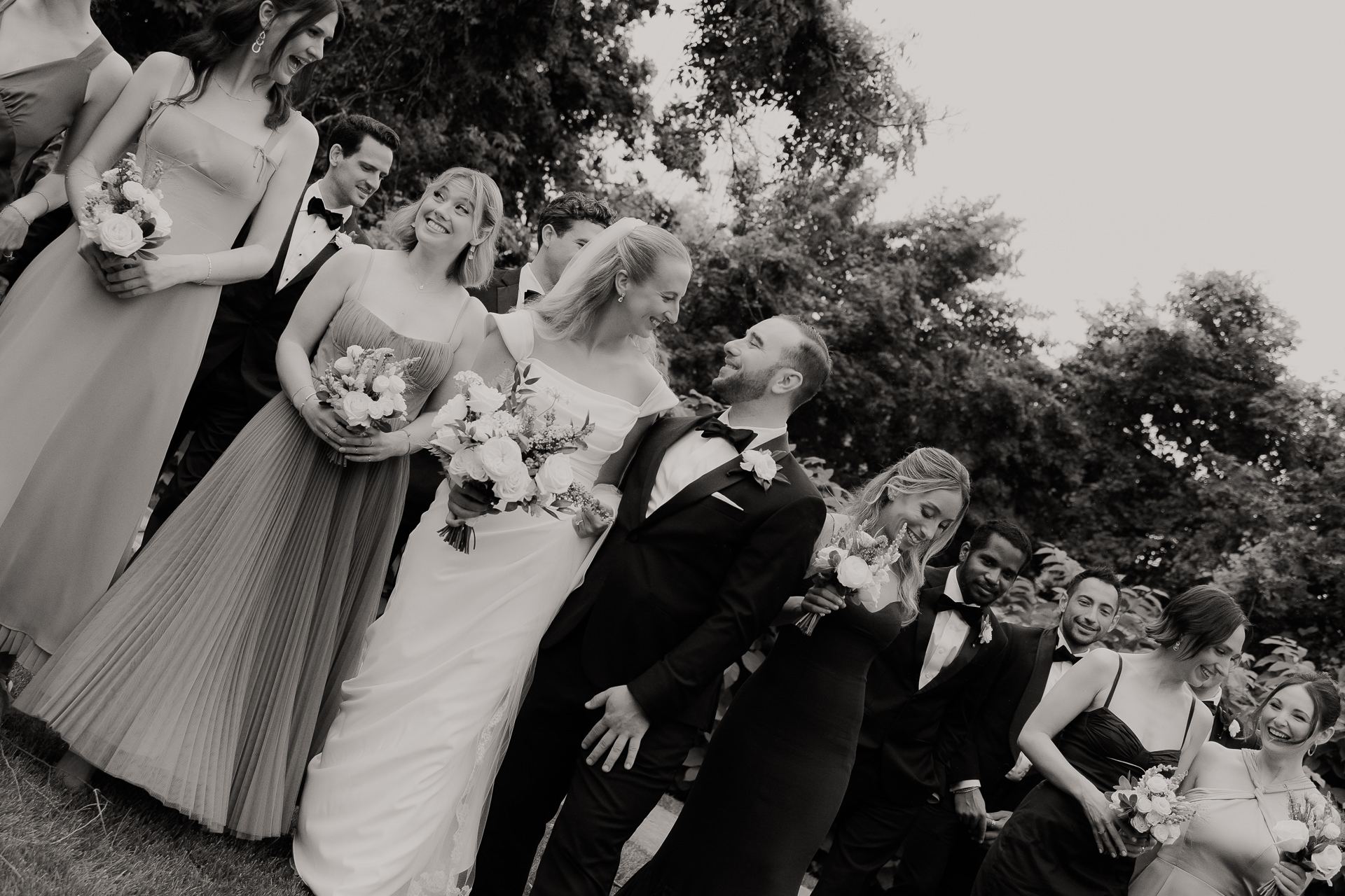 Black and white photograph of the wedding party laughing together at a June Roundhouse wedding