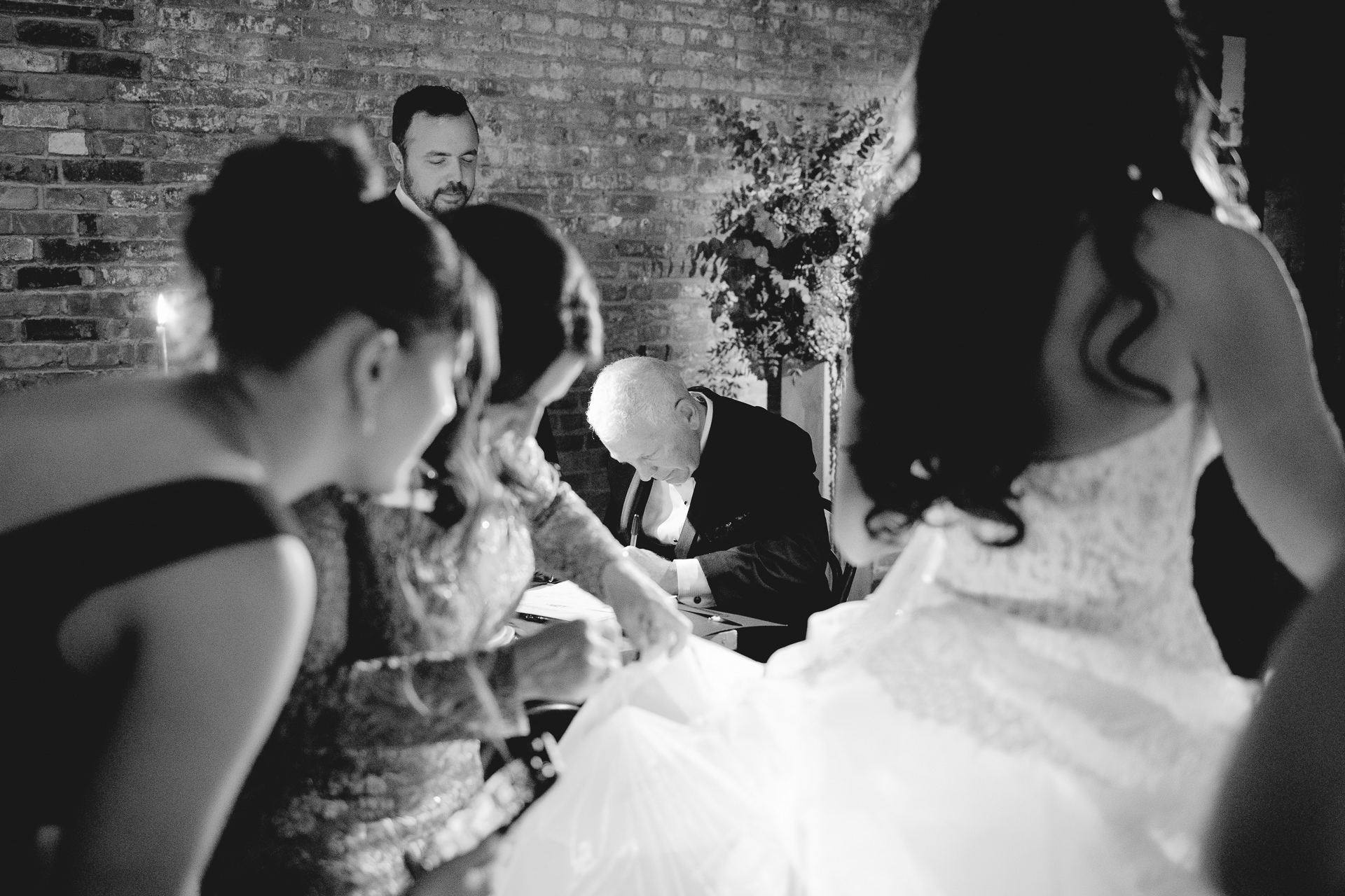 Black and white photograph of guests gathered around the couple at a Wythe Hotel wedding reception