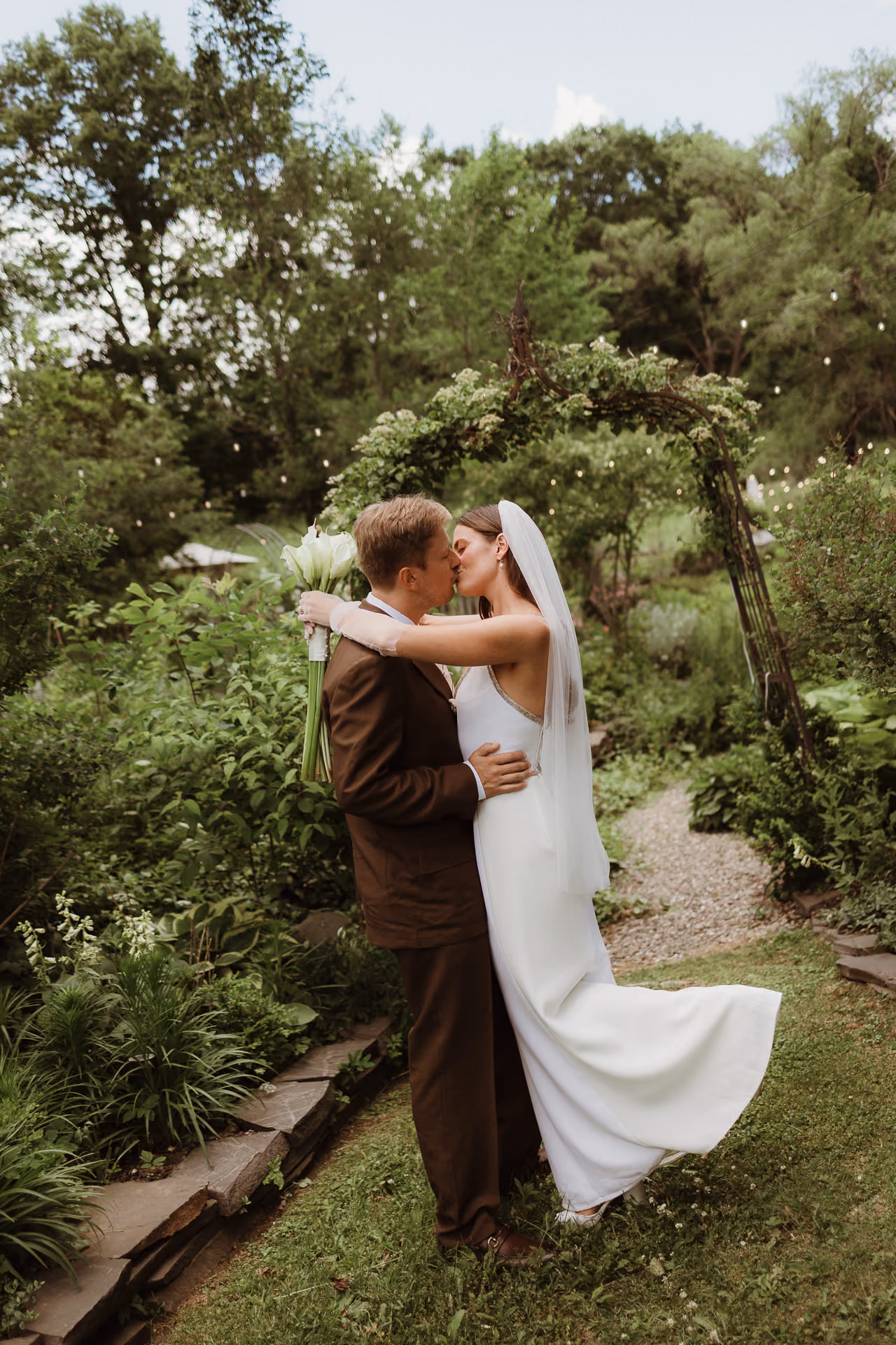 Black and white photograph of a bride and groom kissing under a clear umbrella in the rain