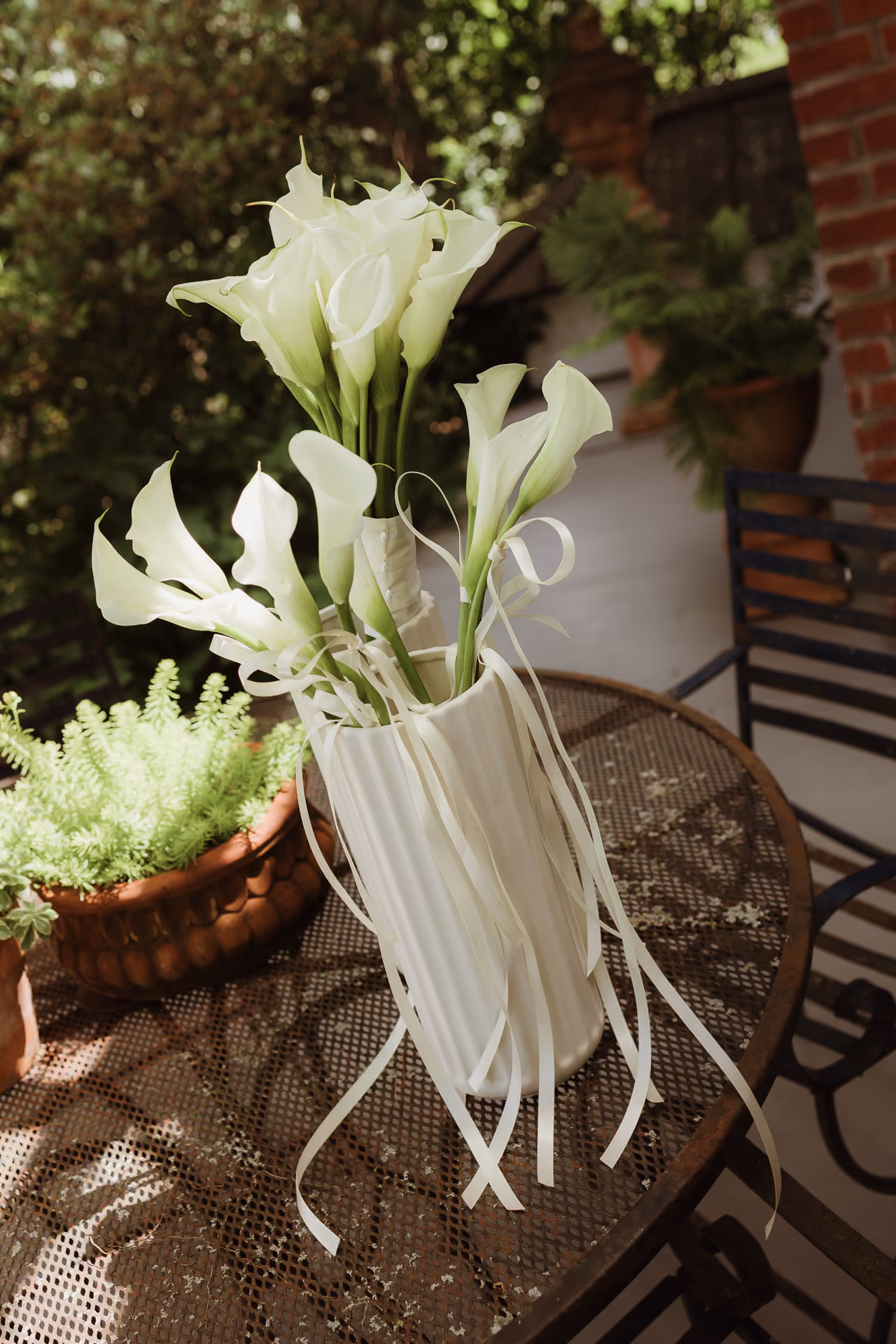 Calla lilies wrapped in white ribbon on a garden table at a summer M and D Farm wedding