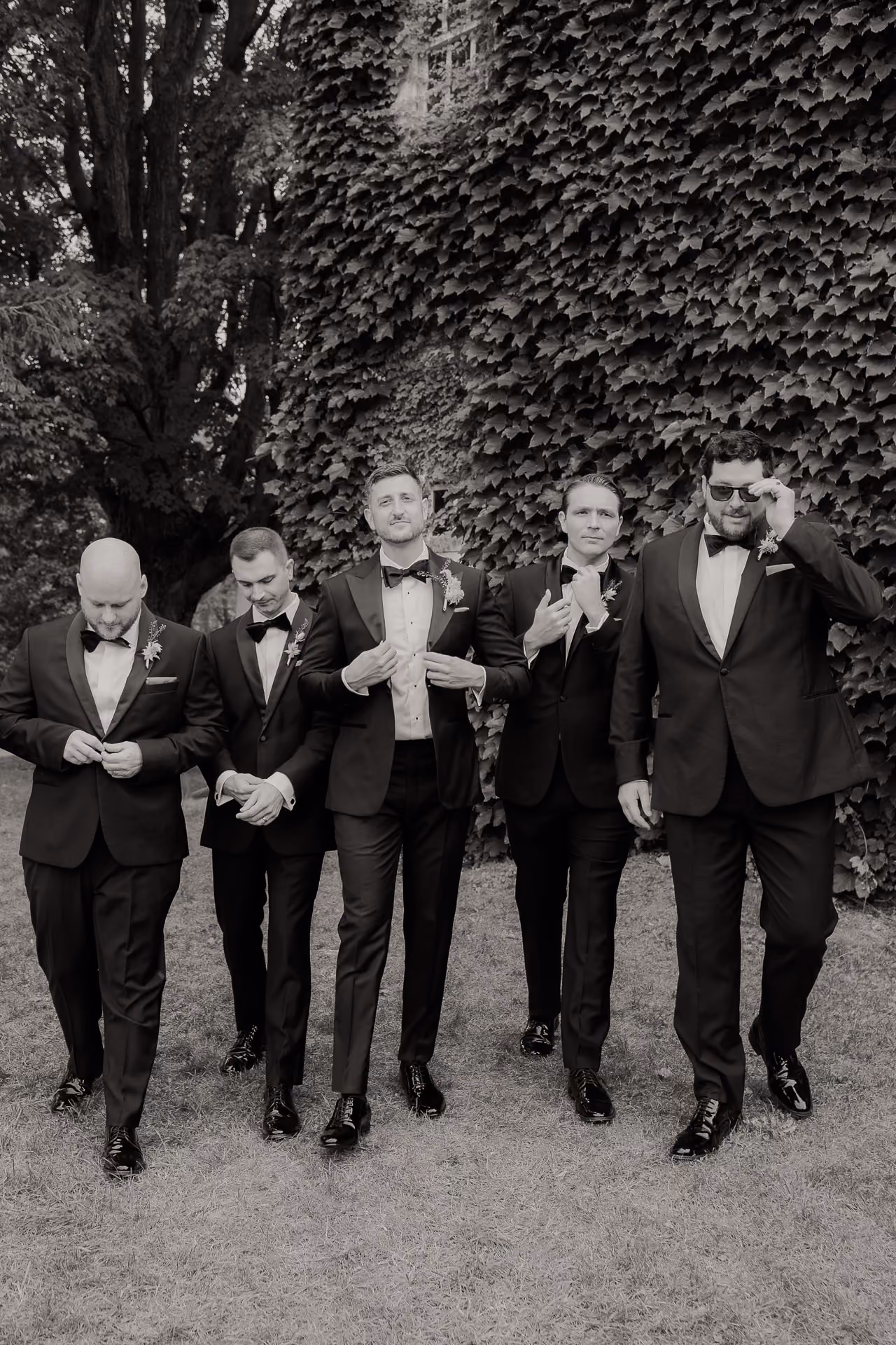 Black and white photograph of the groom and groomsmen walking in tuxedos at Windrift Hall