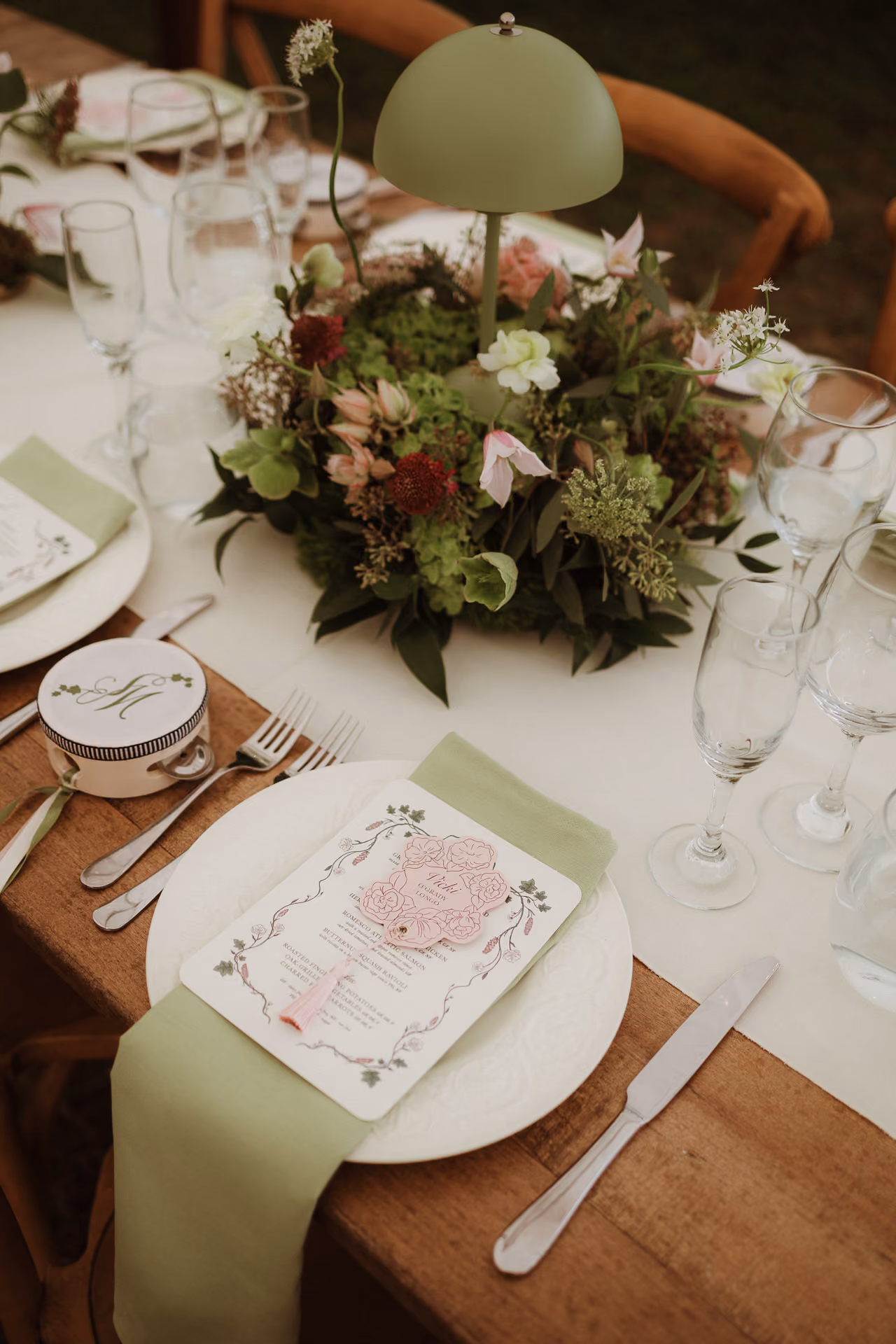 Reception place setting with a floral centrepiece and sage napkins at Windrift Hall