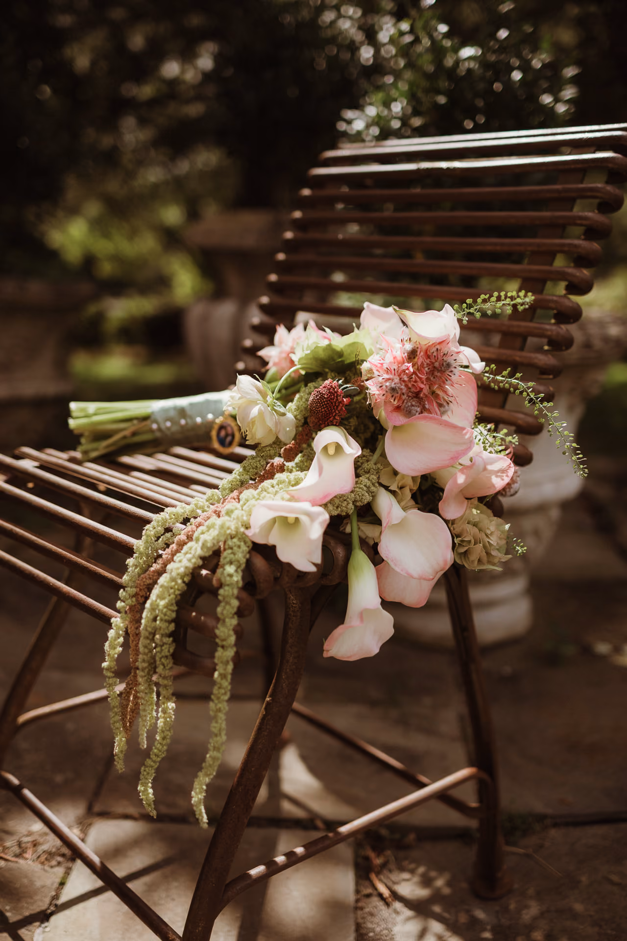Pink calla lily bouquet resting on a garden bench at Windrift Hall