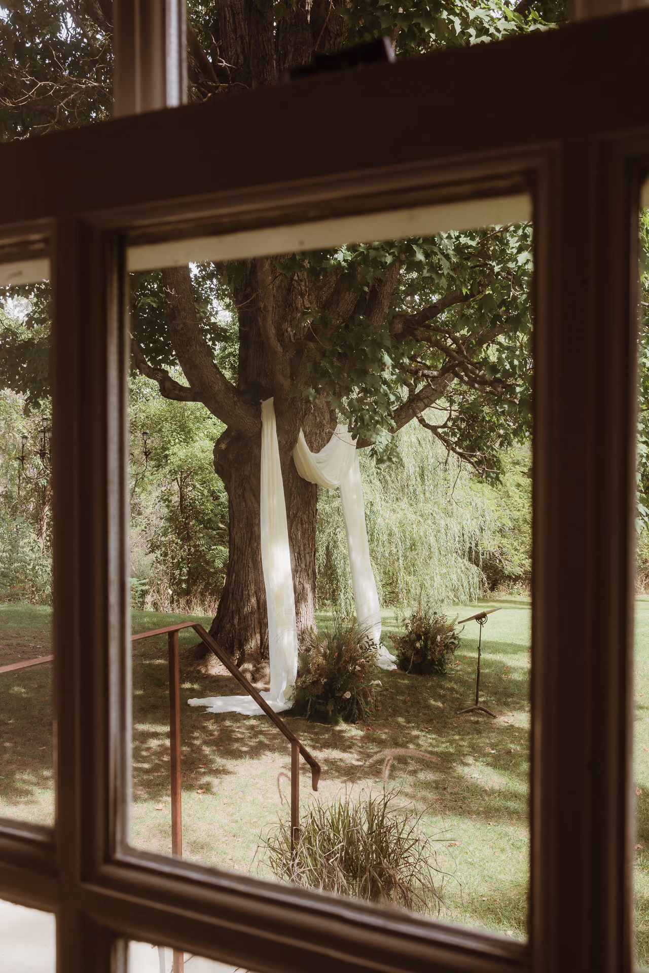 Ceremony seating on the lawn seen through a window at Windrift Hall