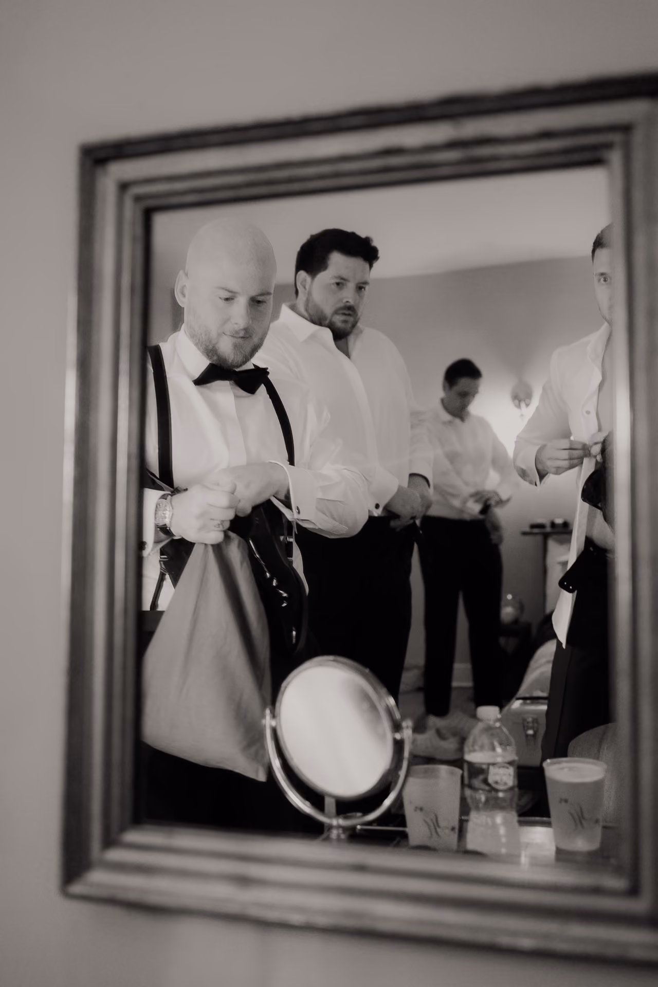 Black and white mirror reflection of the groom and groomsmen getting ready at Windrift Hall