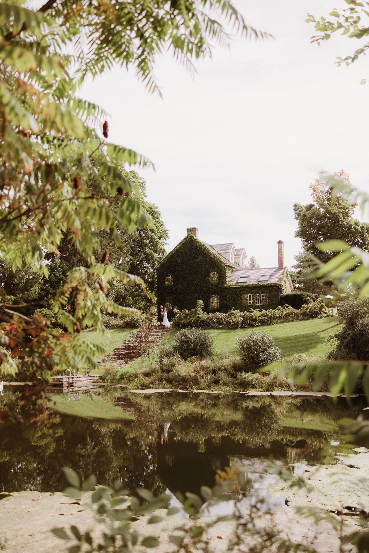 Ivy-covered stone house across a garden pond at Windrift Hall