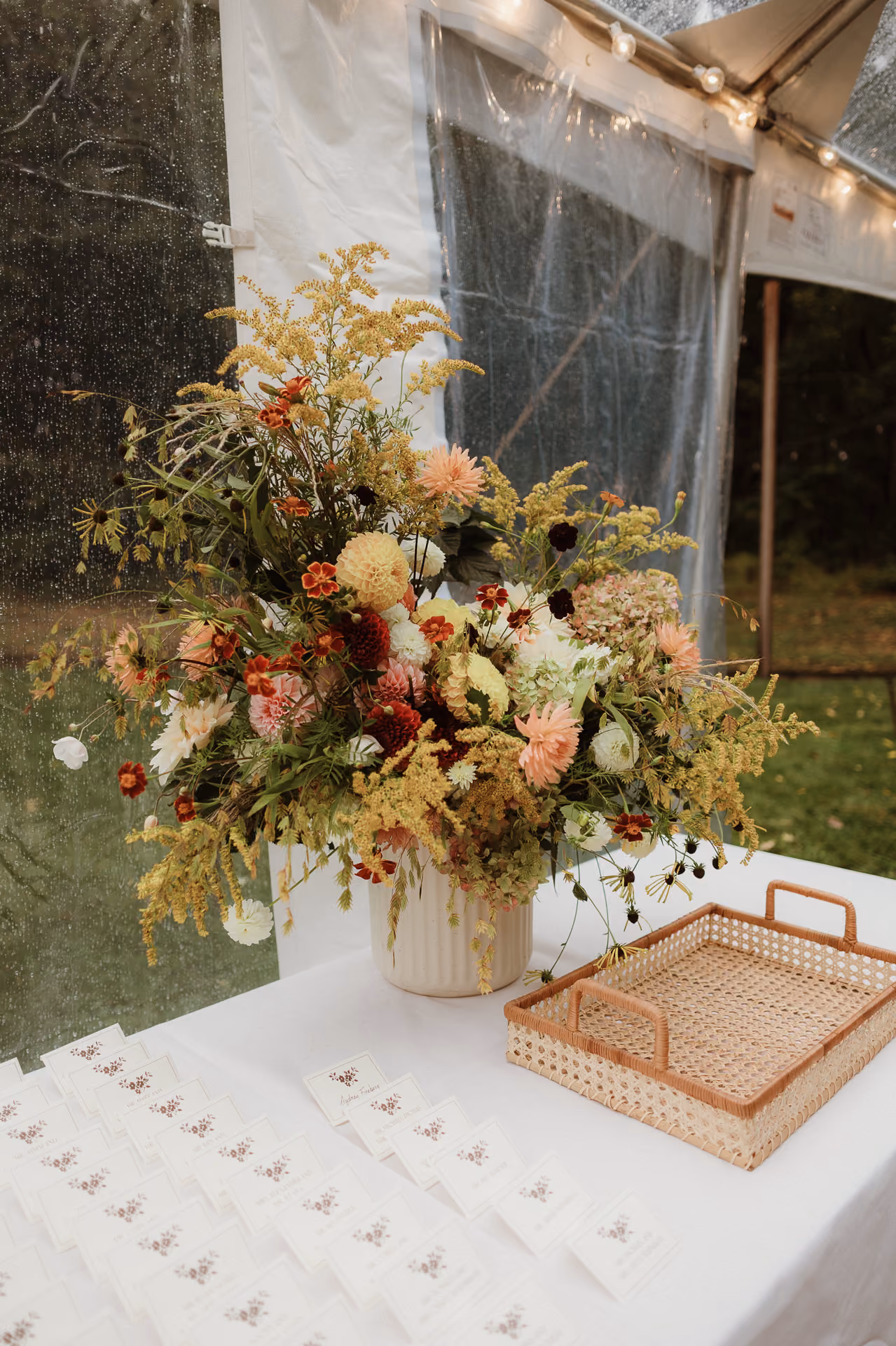 Wildflower arrangement over escort cards in a tent at a Camptown wedding