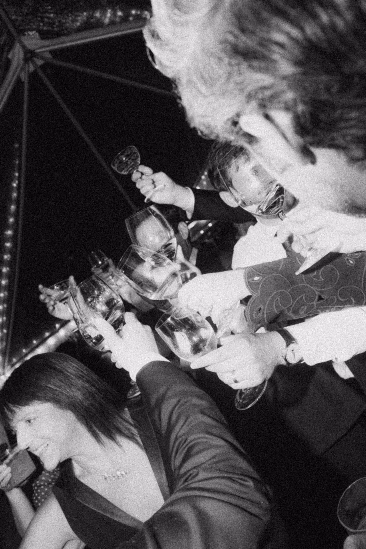 Black and white flash photograph of guests singing and toasting at a Camptown wedding
