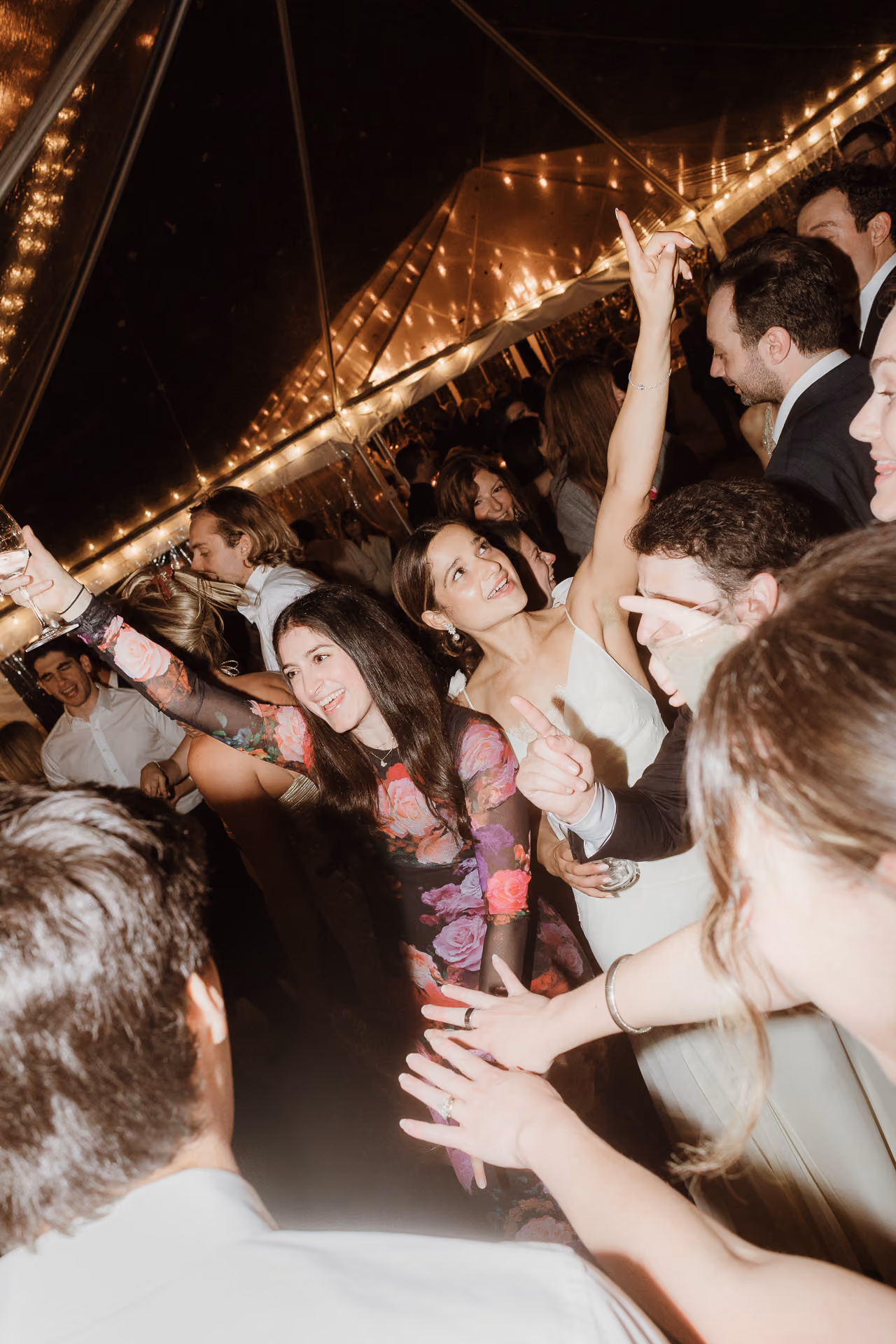 Guests dancing with raised hands under a string-lit tent at a Camptown wedding