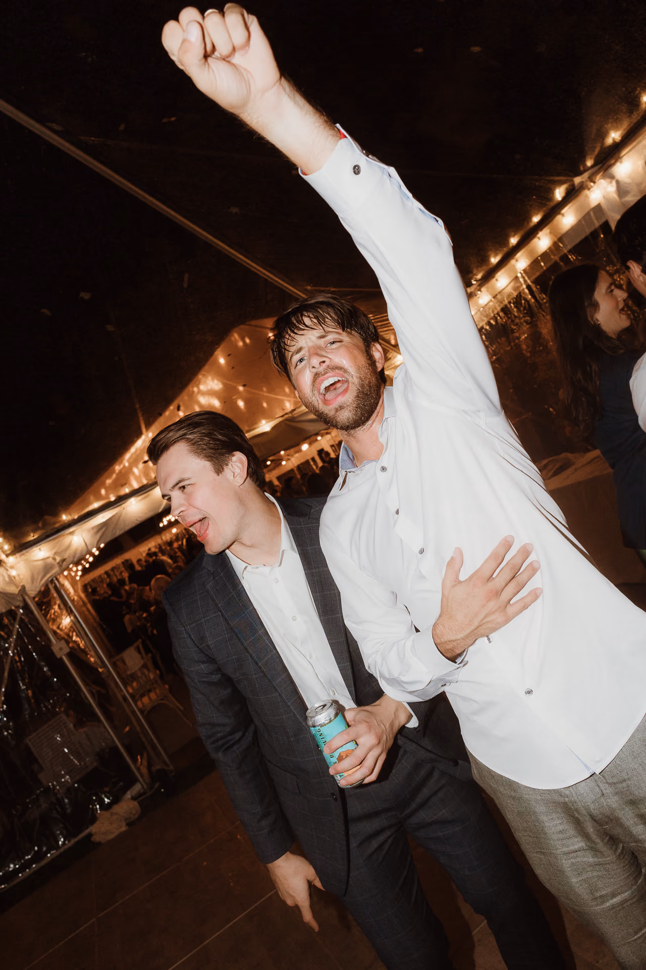 Guests cheering on the dance floor under a string-lit tent at a Camptown wedding