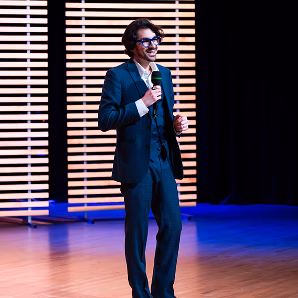 Brian Miller in Blue Suit with Microphone speakinng on stage