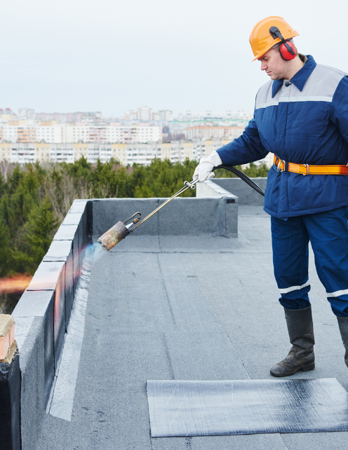 a roofing professional uses a hand-held propane torch to heat the material and adhere it to the surface.