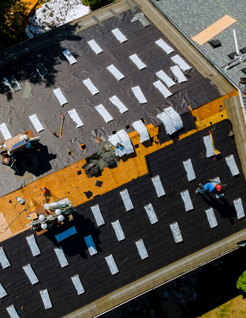 a birds eye view of a single roofer working on a building