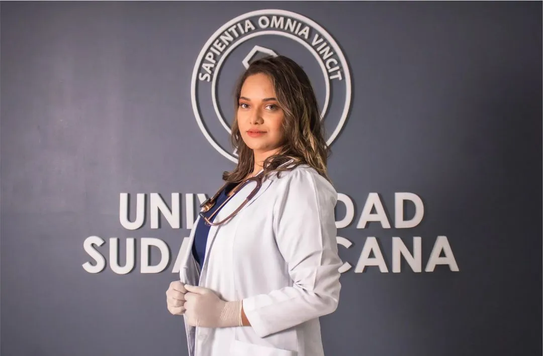 uma médica posando em frente ao letreiro da universidade sul-americana