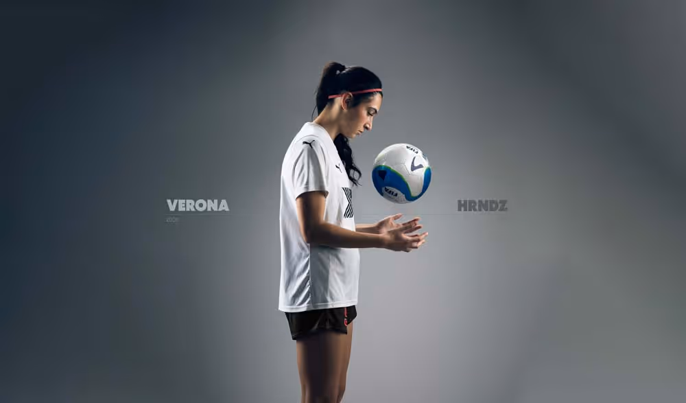 Studio portrait of soccer player balancing ball, minimal background