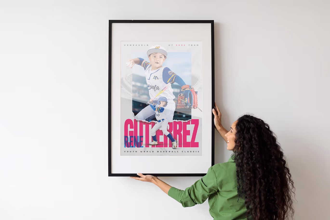 Woman hanging a framed custom baseball poster of a young player named René Gutiérrez wearing the Venezuela team uniform