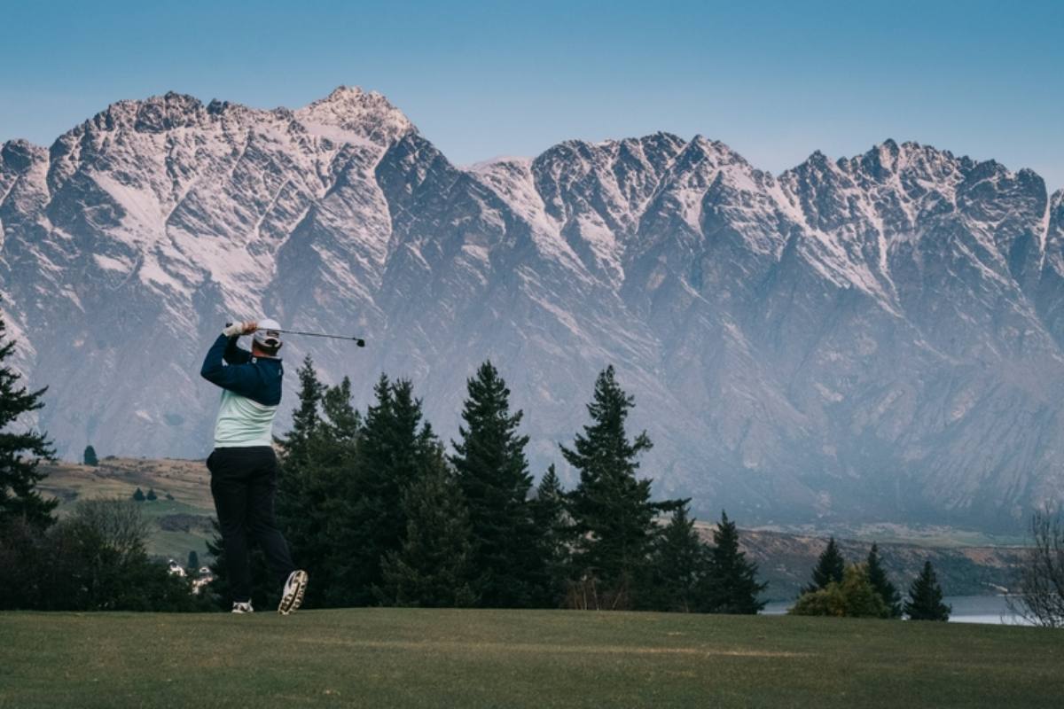 A golfer tees off in front of The Remarkables, Queenstown