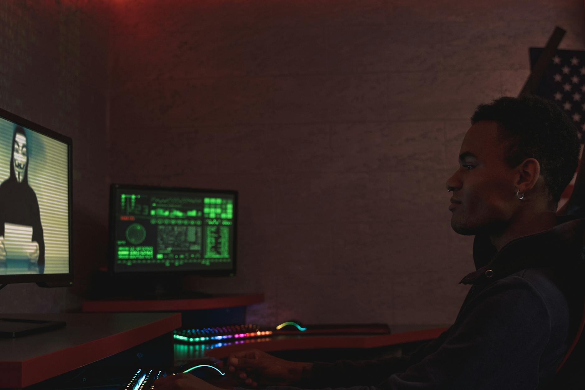 A cybersecurity professional monitors data systems in a dark room, emphasizing protection and vigilance.