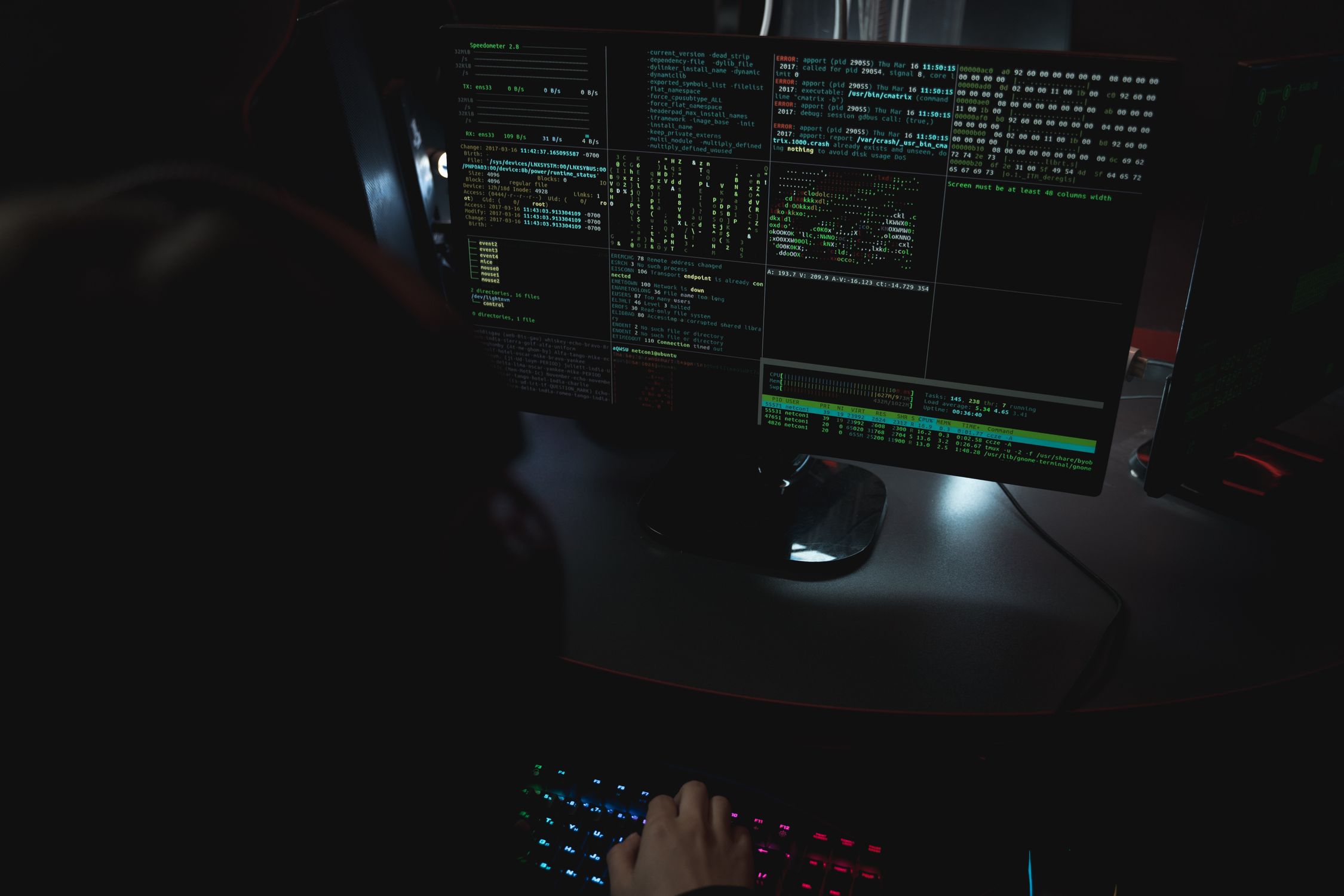 Hands on keyboard in a dark room with lines of code representing cybercrime activity