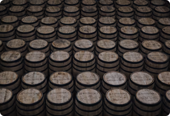 Rows of stacked wooden barrels with Bardstown Distillery labels on top.