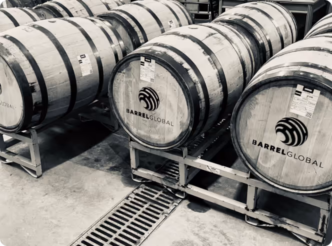 Wooden barrels labeled Barrel Global stored on metal racks in a warehouse.