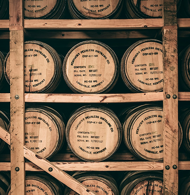 Stacked wooden barrels labeled 'Kentucky Peerless Distilling Co.' in a wooden rack.
