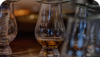 Close-up of whiskey glasses with amber liquid on a wooden bar counter.