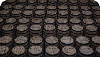 Rows of wooden barrels stacked closely, tops labeled with production details.