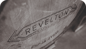Wooden barrel with 'REVELTON DISTILLERY' stamped on its side in a vintage style.