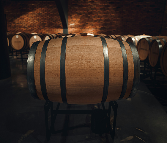 Wooden wine barrel with metal bands in a dimly lit cellar with more barrels in the background.