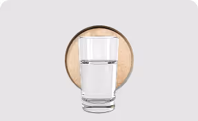 Glass of clear water sitting in front of a wooden coaster on a light gray background.