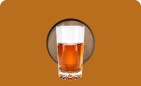 Glass of amber liquid with an ice cube on a brown surface with circular wood texture behind.