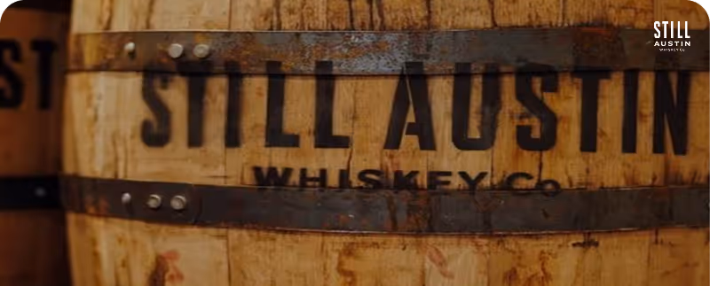 Wooden whiskey barrel with metal bands labeled Still Austin Whiskey Co.