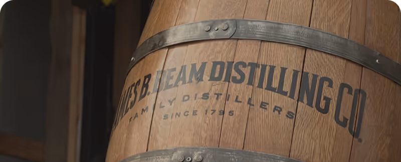 Wooden barrel with metal bands labeled 'JAMES B. BEAM DISTILLING CO. FAMILY DISTILLERS SINCE 1795'.