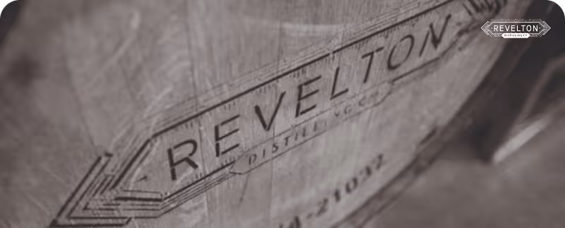 Close-up of a wooden barrel with the Revelton Distilling Co. logo stamped on it.