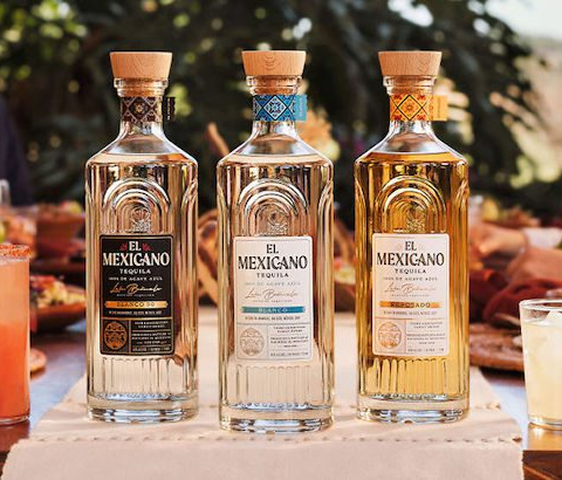 Three El Mexicano tequila bottles with wooden caps on a table outdoors with blurred background.