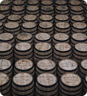 Rows of aged wooden barrels stacked closely, each with a number and text on the top surface.