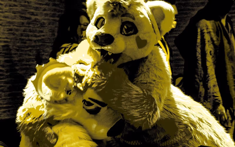 A fursuiter playfully grabs the head of another fursuiter. Photo by SleepyDef.
